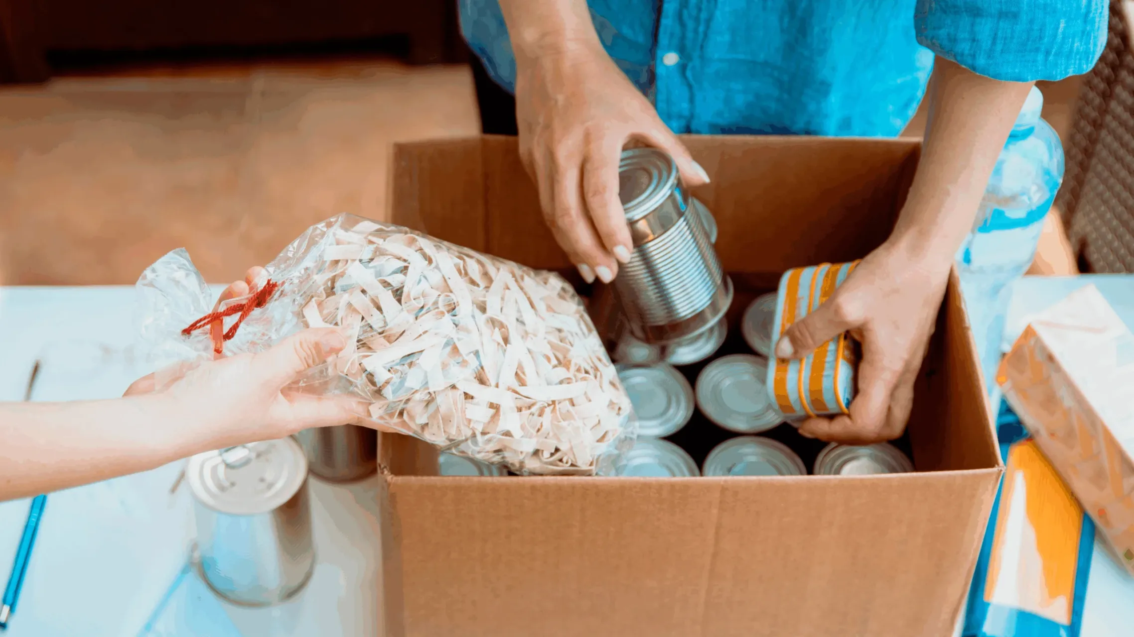 Food bank volunteers putting food into a cardboard box