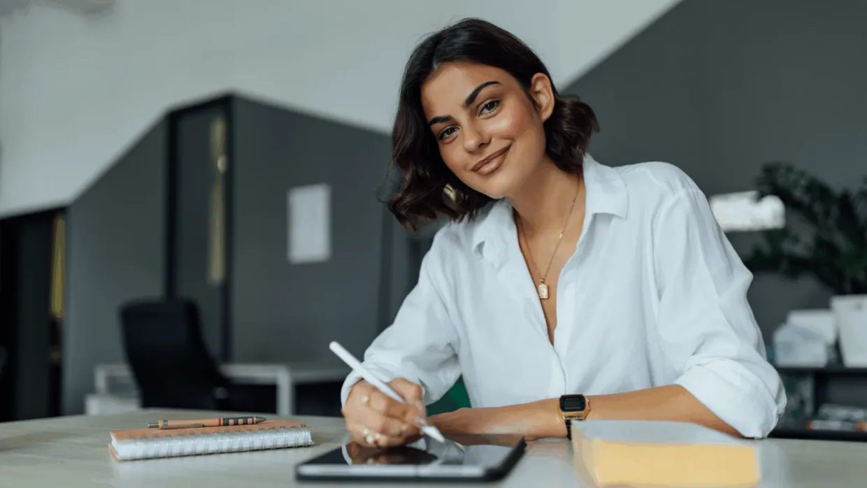 Female smiling at desk working on tablet