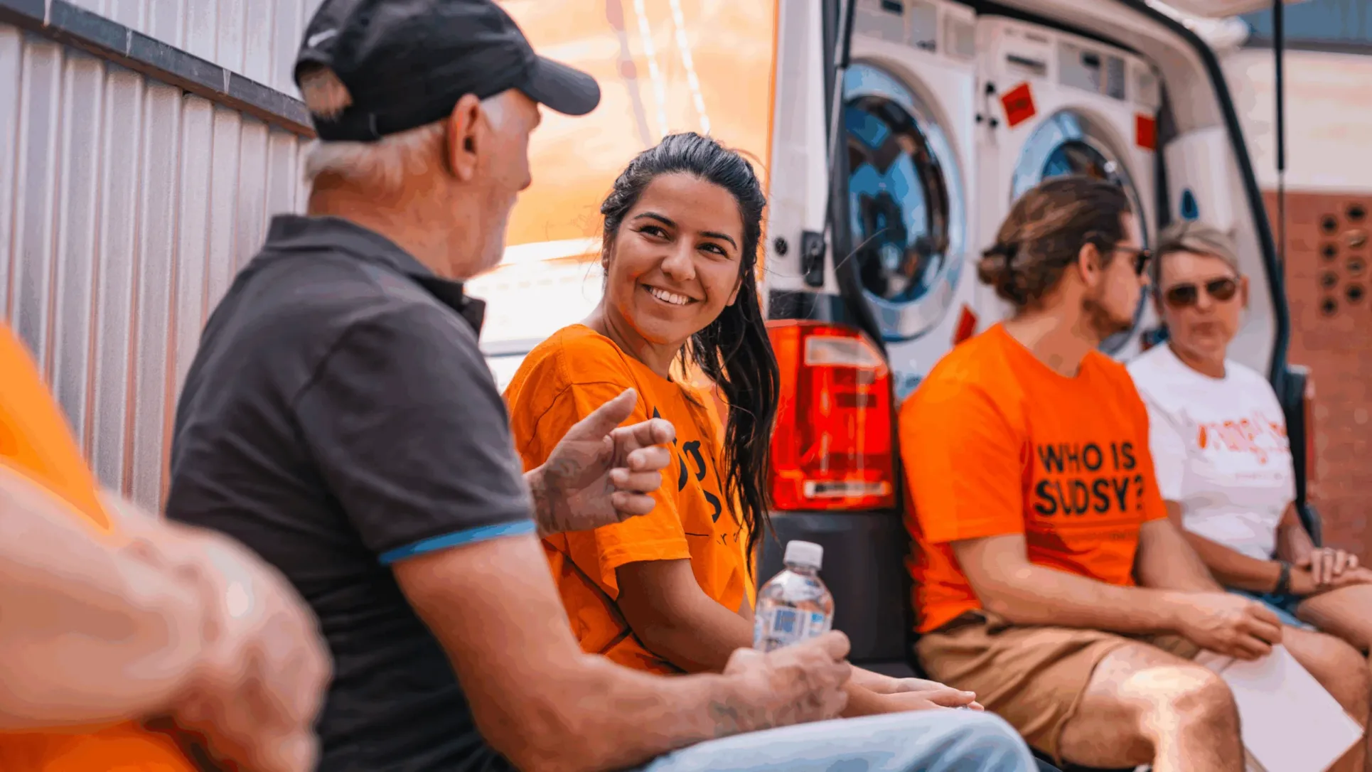 Orange Sky volunteer smiling and talking to one of the Orange Sky 'friends' out the front of a mobile laundry