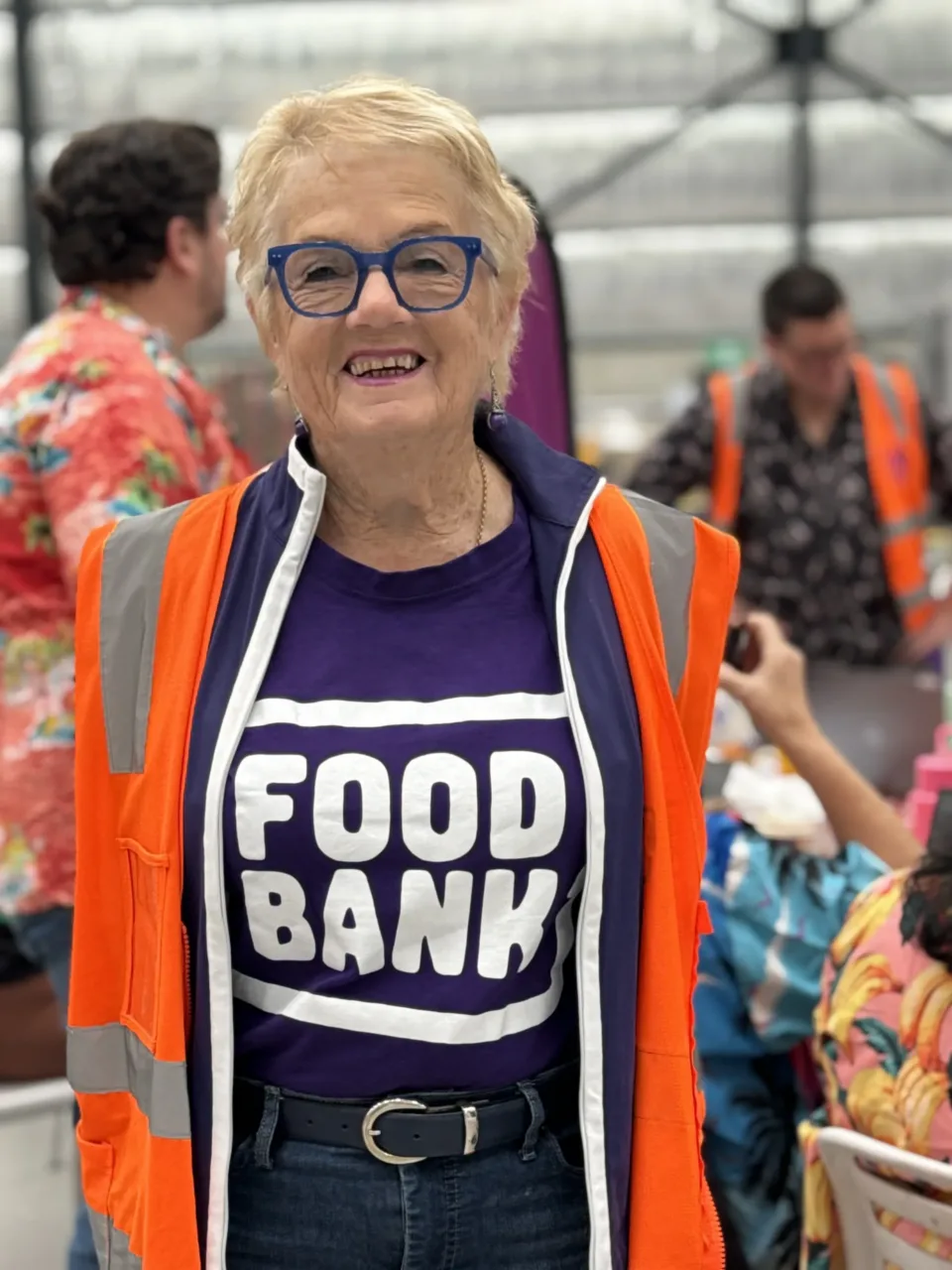 Foodbank Victoria volunteer in a warehouse wearing a high vis vest smiling at camera