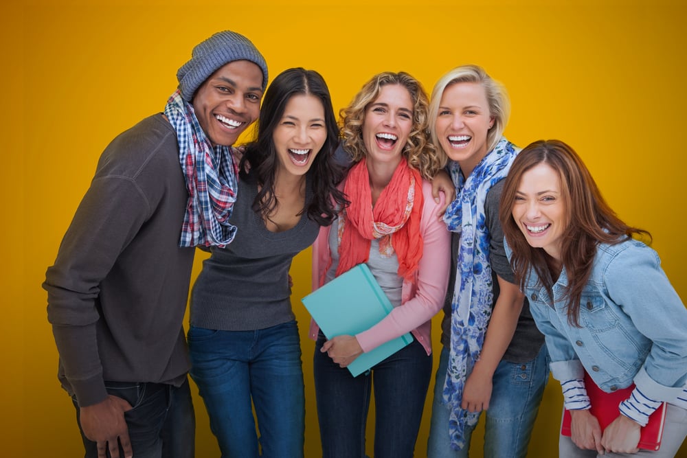Cheerful group of friends laughing together on yellow background-1