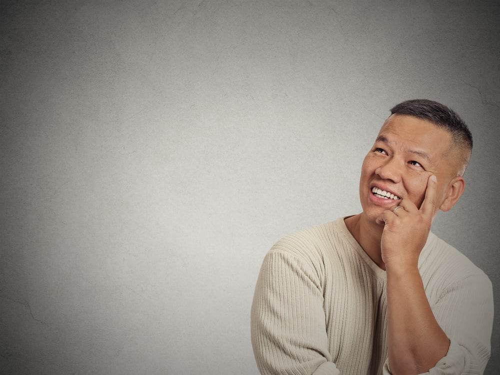 Portrait happy handsome man thinking looking up isolated grey wall background with copy space. Human face expressions, emotions, feelings, body language, perception