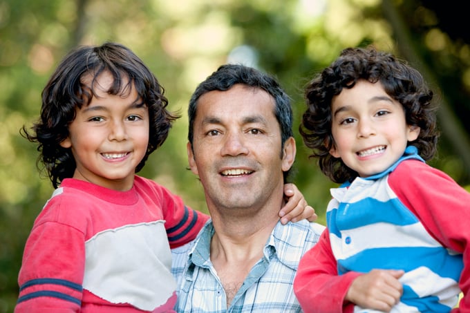 Portrait of a father carrying his sons outdoors and smiling