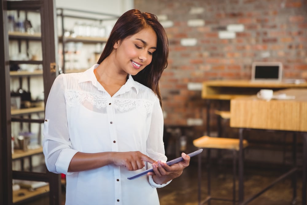 Smiling young businesswoman holding a tablet in her office