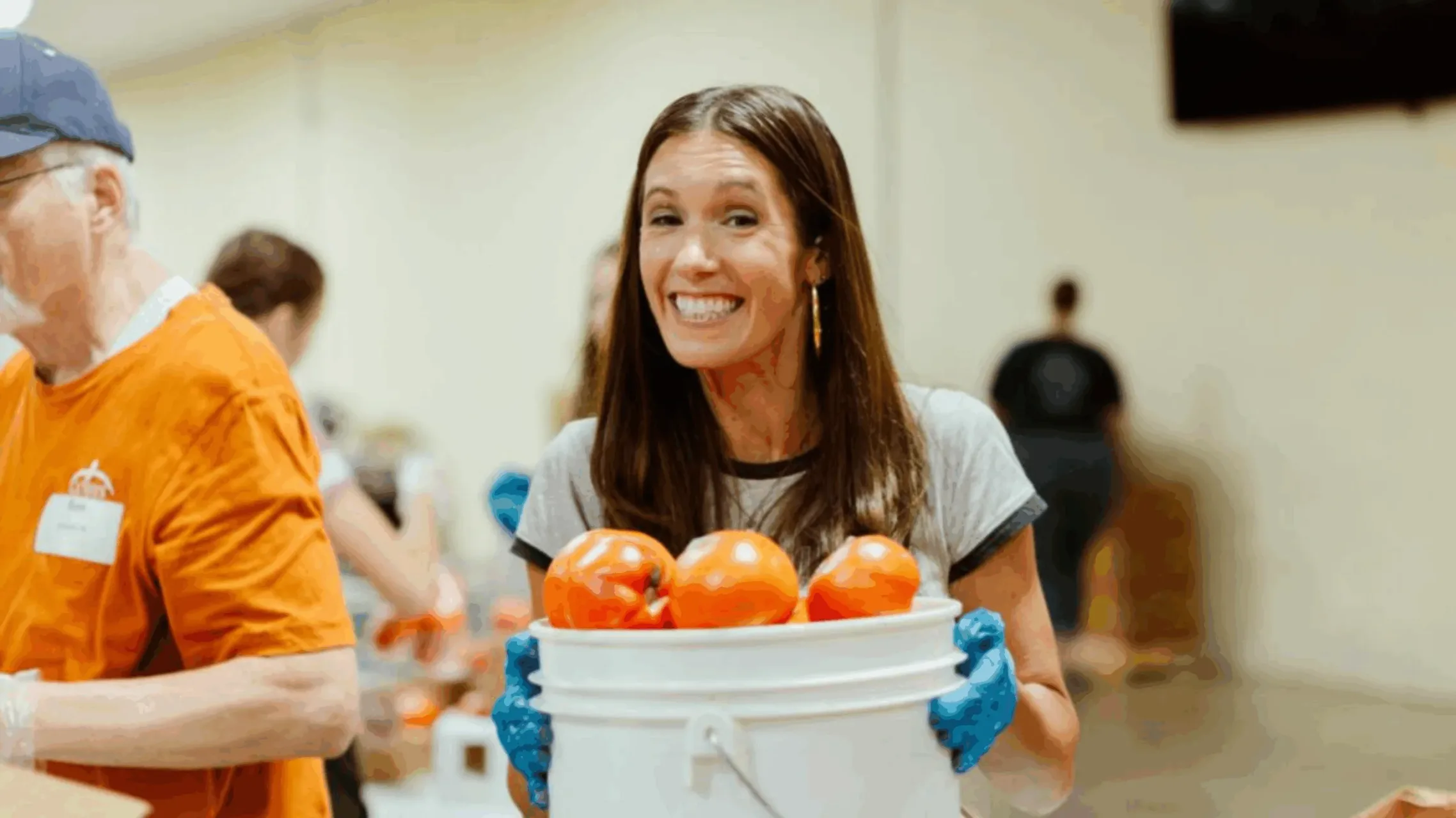 Blessings of Hope volunteer holding bucket of oranges in bucket