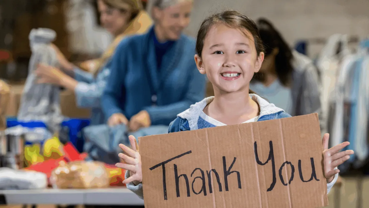 Young girl in food bank holding a thank you sign
