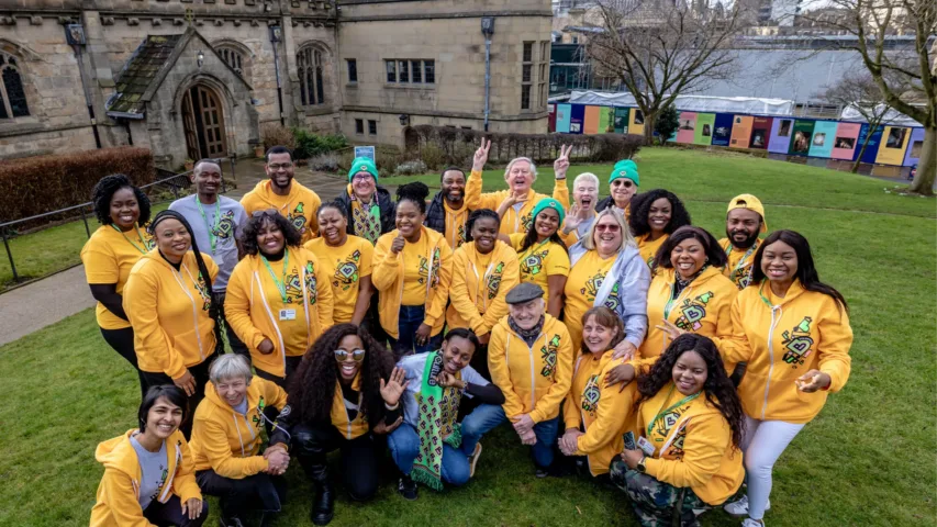 Large group of Bradford 2025 volunteers in their yellow volunteer uniforms smiling at camera