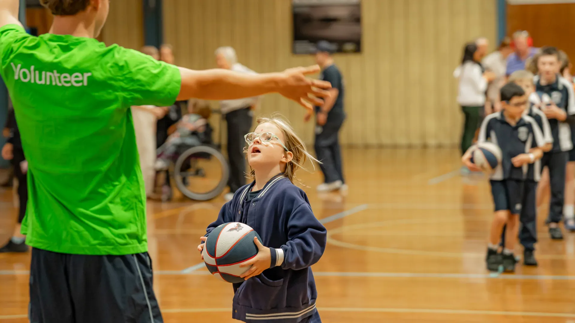Disability Sports Australia volunteers helping out at a kids basketball event with little girl shooting for a goal