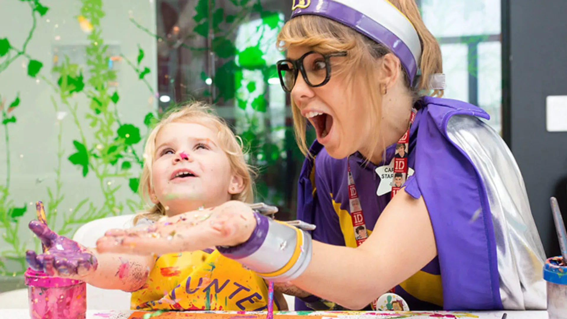 Starlight Children's Day volunteer dressed up as a super hero helping out sick child in hospital